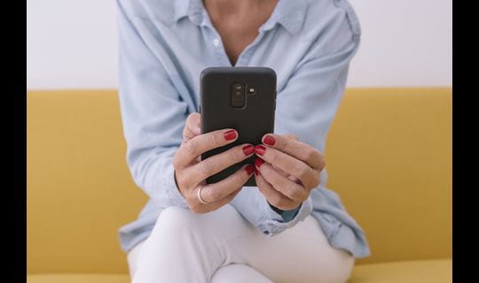woman using smartphone on yellow couch